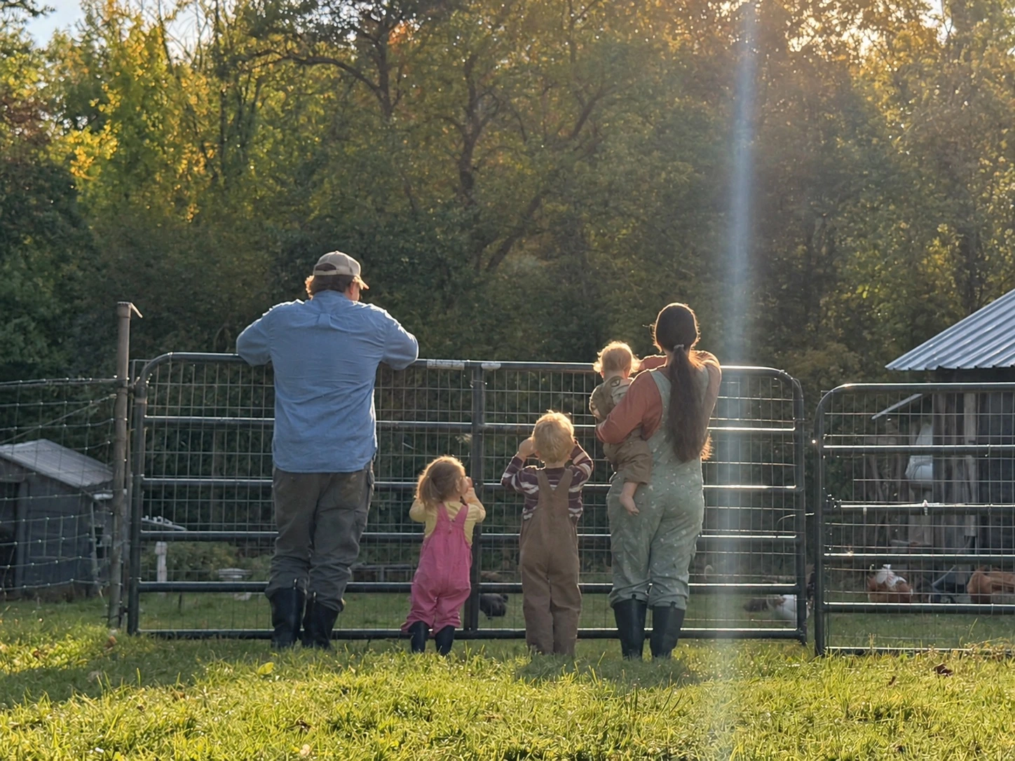 The Forcier family standing together at the pasture gate in the autumn sunshine